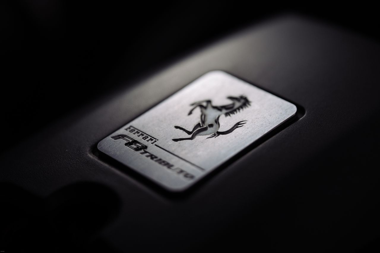 A close-up view of a metallic car emblem badge featuring a prancing horse, representing luxury and speed.